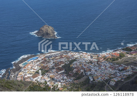 Aerial view of old town Garachico from Mirador de Garachico view point. Colorful houses and harbor. Ocean shore with lava rock pools. Popular tourist destination, Tenerife Canary Islands. Aerial view of old town Garachico from Mirador de Garachico view point. Colorful houses and harbor. Ocean shore with lava rock pools. Popular tourist destination, Tenerife Canary Islands. 126118978