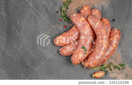 Raw sausages or bratwurst with spices for grill or barbeque on a black stone table, top view Raw sausages or bratwurst with spices for grill or barbeque on a black stone table, top view 126120290