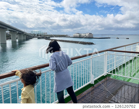 Back view of sisters gazing at the blue sea from the deck of a ship 126120702