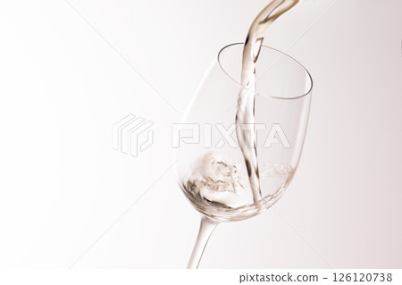 Pour white wine into the glass 126120738