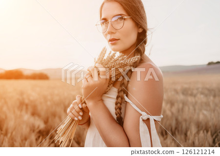 Woman wheat field. Agronomist, Woman farmer check golden ripe barley spikes in cultivated field. A woman is holding a bunch of wheat in her arms. 126121214