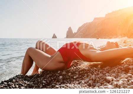 Woman in Red Bathing Suit Relaxing on a Pebble Beach 126121227
