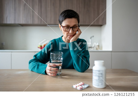 Apathetic lonely woman looking at medication hesitating over mental pain and emotional battle Apathetic lonely woman looking at medication hesitating over mental pain and emotional battle 126121255
