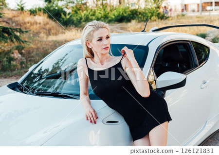 woman in black summer dress at the steering wheel of a sports car 126121831
