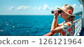 Senior woman in summer dress and hat on deck of cruise liner looking at sea through binoculars. Travel, tourism. Banner with copy space 126121964