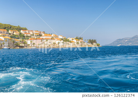 Korcula island in Croatia, Europe. Coastal townscape: azure sea meets quaint architecture against a clear blue sky. Serene scenery invites exploration and relaxation. 126122374