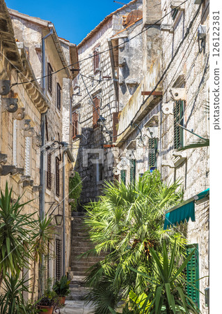 Orebic town at coast of the Peljesac peninsula in Croatia, Europe. Charming old town alleyway with stone buildings, stairs, and lush greenery, showcasing European architecture and a sense of history. Orebic town at coast of the Peljesac peninsula in Croatia, Europe. Charming old town alleyway with stone buildings, stairs, and lush greenery, showcasing European architecture and a sense of history. 126122381