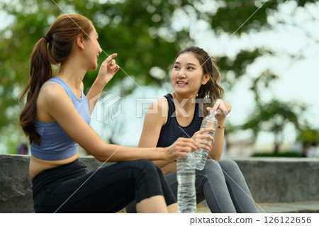 Active women in sportswear hydrating after completing their outdoor fitness routine 126122656