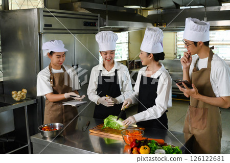 Chef teacher demonstrating vegetable preparation technique in a professional kitchen Chef teacher demonstrating vegetable preparation technique in a professional kitchen 126122681