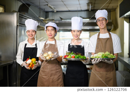 Group of culinary students proudly holding fresh vegetables, ready for their cooking class 126122706