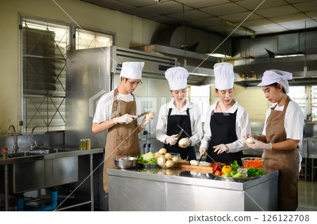 Culinary instructor guiding students on proper knife techniques in a training session 126122708