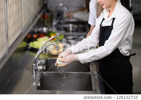 Smiling young chefs learning kitchen hygiene and teamwork in a professional cooking school Smiling young chefs learning kitchen hygiene and teamwork in a professional cooking school 126122710