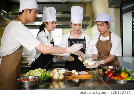 Culinary students peel and organize onions during a hands on cooking class Culinary students peel and organize onions during a hands on cooking class 126122725