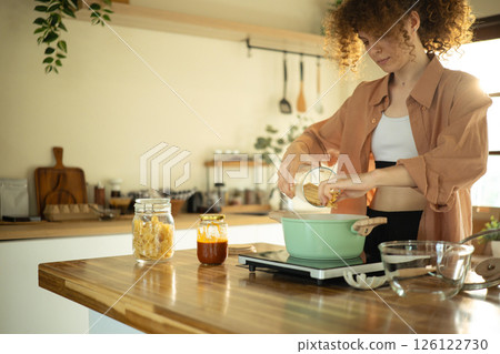 Young woman with curly haired preparing a meal in a bright home Young woman with curly haired preparing a meal in a bright home 126122730