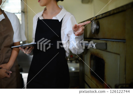 Chef teacher explains temperature control using a commercial oven during culinary class Chef teacher explains temperature control using a commercial oven during culinary class 126122744