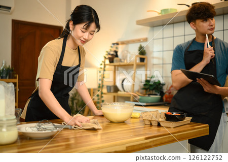 Happy couple preparing pancake batter together in a cozy kitchen Happy couple preparing pancake batter together in a cozy kitchen 126122752