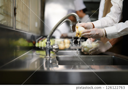 Smiling young chefs learning kitchen hygiene and teamwork in a professional cooking school Smiling young chefs learning kitchen hygiene and teamwork in a professional cooking school 126122763