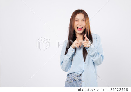Cheeky woman makes a finger bang gesture as friendly woman winks and smiles, playfully pointing like she saying what up or you are the one, isolated on white background. 126122768