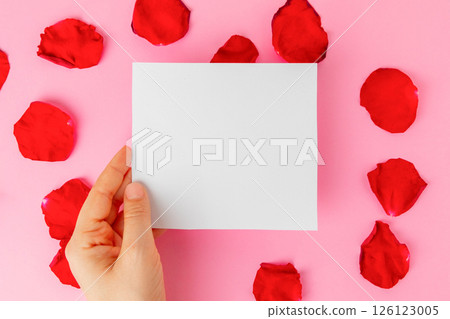 Hand holding a blank paper on romantic pink background 126123005
