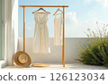 White women's clothes hang on a hanger on the terrace, a hat lies nearby, a clear sky in the background 126123034