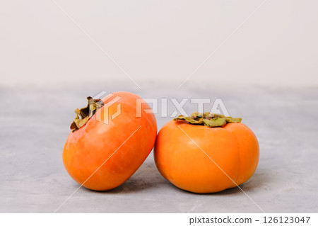 Ripe persimmon fruits on neutral light background 126123047