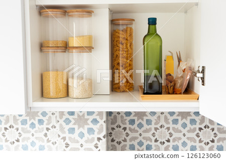 Organized kitchen pantry shelf with grains, olive oil bottle and pasta 126123060