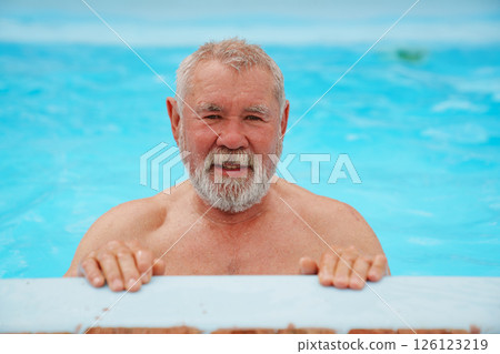 An elderly man with a gray beard in the pool. 126123219