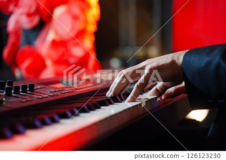 Men's hands play the keys of an electronic piano.  126123230