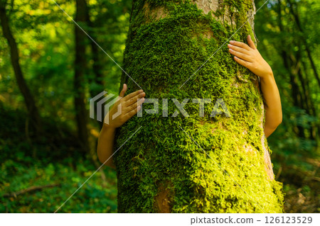 Human Hands Hugging Mossy Tree in Forest Human Hands Hugging Mossy Tree in Forest 126123529