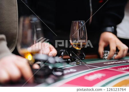 Players share excitement while gambling at a vibrant casino table Players share excitement while gambling at a vibrant casino table 126123764
