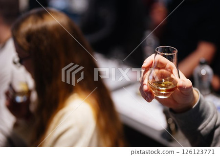Enjoying whiskey tasting at a cozy bar with friends in the evening 126123771