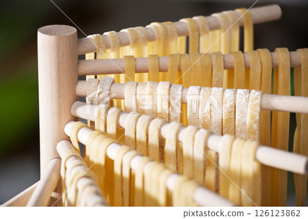 Homemade noodles hanging on wooden dryer rack closeup low angle view 126123862