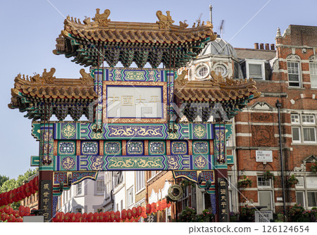 Beautiful view of London Chinatown entrance gate in traditional chinese design with glazed yellow tiles, a golden dragon, painted panels, two white jade plaques and red lanterns. 126124654