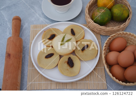 These soft, round cakes are garnished with raisins and pandan leaves, adding both flavor and visual appeal 126124722