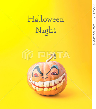 Pumpkin with a painted face is on a yellow background with Halloween Night Pumpkin with a painted face is on a yellow background with Halloween Night 126125535