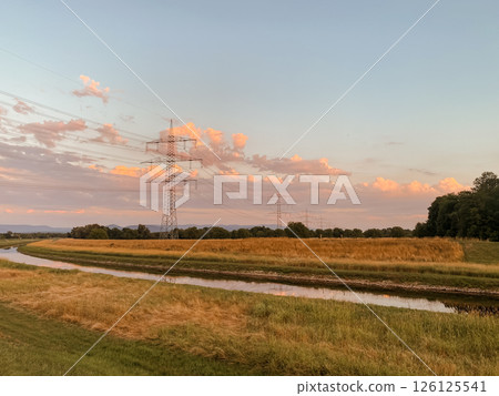 Power line tower is in the background of a field Power line tower is in the background of a field 126125541