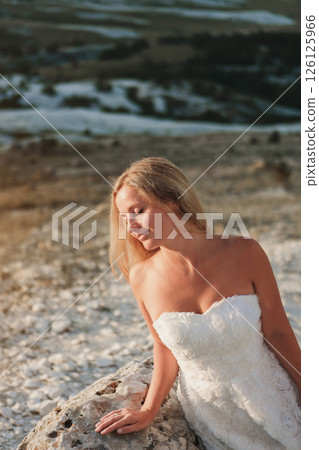 a woman in a white dress, a bride on a mountain with a blue sky. Beautiful nature, freedom, enjoyment of life. High quality photo 126125966