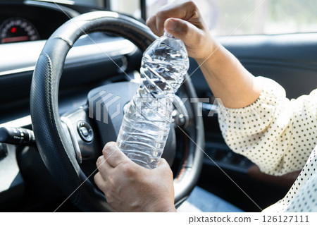 Asian woman driver hold cold water for drink in car, dangerous and risk an accident. Asian woman driver hold cold water for drink in car, dangerous and risk an accident. 126127111
