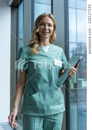Pretty blonde female doctor in green lab coat near the window in the hospital 126127245