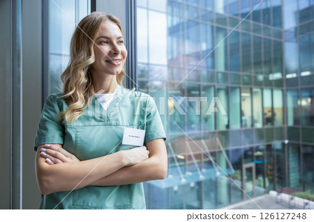 Pretty blonde female doctor in green lab coat near the window in the hospital 126127248