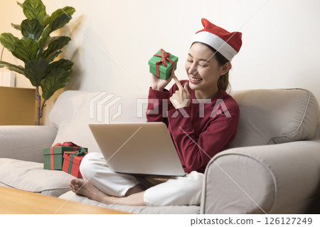 Celebrate on Christmas or new year season, asian woman hold a present box make video call during social distance, showing present, gift box on merry x'mas. 126127249