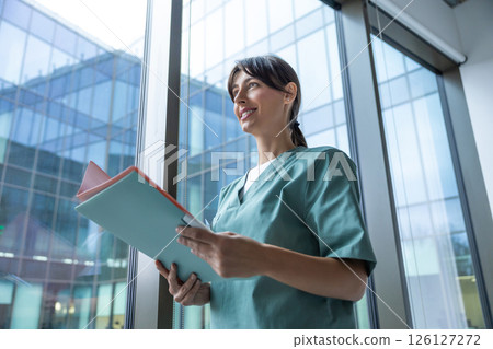 Cute long-haired blonde caucasian woman in lab coat in the clinic corridor 126127272