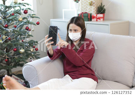 Beautiful Asian woman feel lonely and depressed with smartphone at home during Christmas holiday season. 126127352