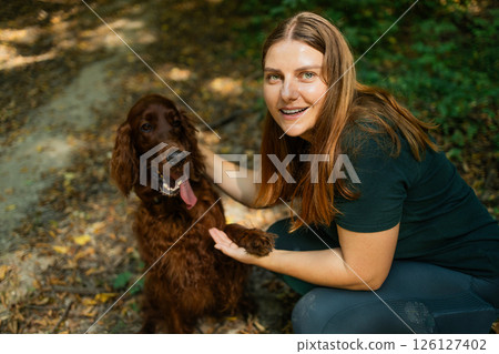 Happy Woman Holding Dogs Paw in Forest Happy Woman Holding Dogs Paw in Forest 126127402