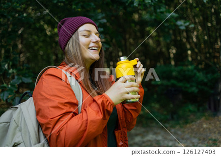 Smiling Woman in Outdoor Gear Drinking from Reusable Bottle 126127403