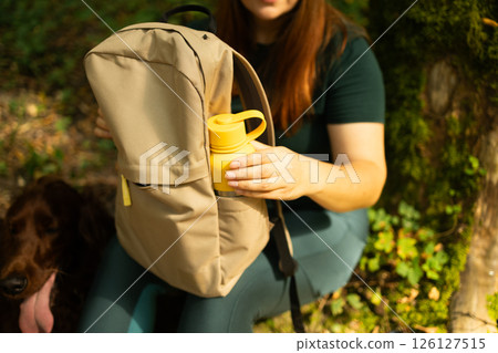 Woman Reaching for Water Bottle in Backpack During Forest Break 126127515