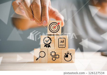Hand skillfully stacking wood blocks on a table, representing the concept of business strategy and Action plan. Copy space available for professional use. 126127534