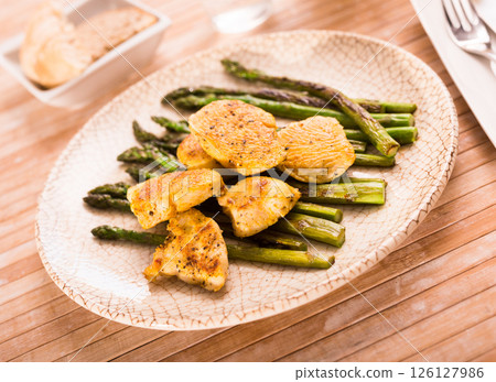 Cooked dish. Chicken nuggets with green asparagus on plate 126127986
