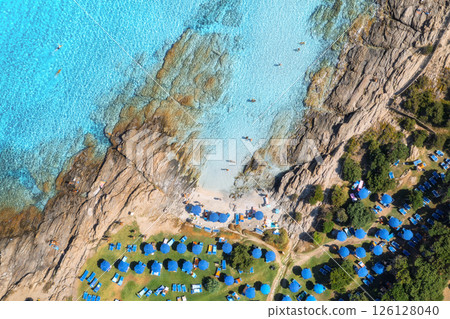 Aerial view of sea bay, sandy beach with umbrellas at sunset 126128040