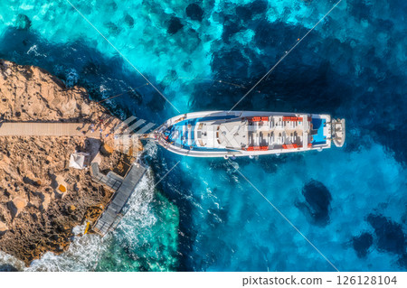 Aerial view of boat and rocky sea coast on sunny summer day Aerial view of boat and rocky sea coast on sunny summer day 126128104